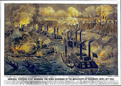 A line of about a dozen Union gunboats on the Mississippi River exchange fire with the town above on a cliff