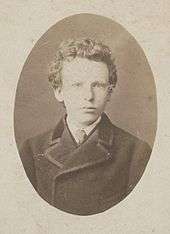 Black-and-white formal head shot photo of the artist as a boy in jacket and tie. He has thick curly hair and very pale-coloured eyes with a wary, uneasy expression.