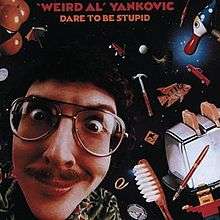 The cover for Dare to Be Stupid features "Weird Al" Yankovic's face against a backdrop of space. Scattered around his head are various items, such as a fish, a toaster, a toothbrush, and a hammer.