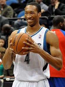 Wesley Johnson smiling and griping a basketball, standing upright