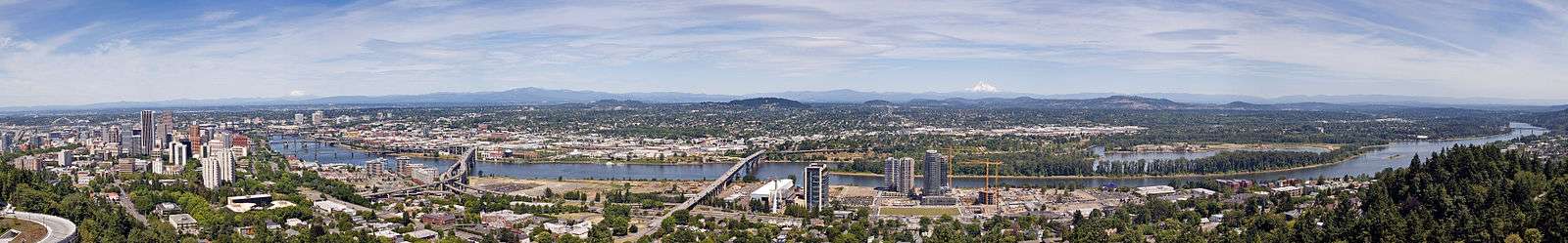 A panorama of Portland, with many buildings on either side of the Willamette River, with a number of bridges crossing it