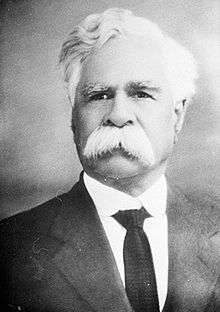 Photographic portrait of a man with white hair and moustache