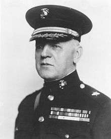 A black and white image of Williams Dion, a white male in his Marine Corps dress blue uniform. He is wearing a hat and several ribbons.