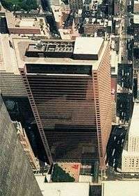 Aerial view of a skyscraper with a trapezoidal cross section and a brown glass exterior
