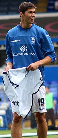 A dark-haired white man wearing a blue training top and white shorts.