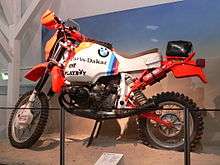  Race-prepared R80G/S motorcycle, with Paris Dakar, Elf, and Playboy stickers. Displayed on a stand in a museum
